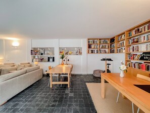 Un salon moderne avec un canapé, une table à manger et une bibliothèque remplie de livres.