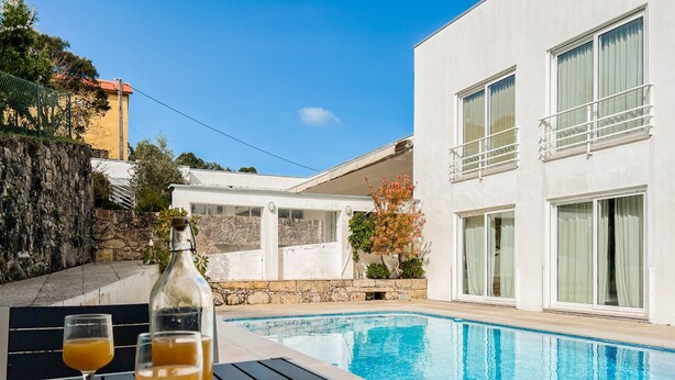 Une piscine, avec une table et deux verres de jus d’orange au premier plan.