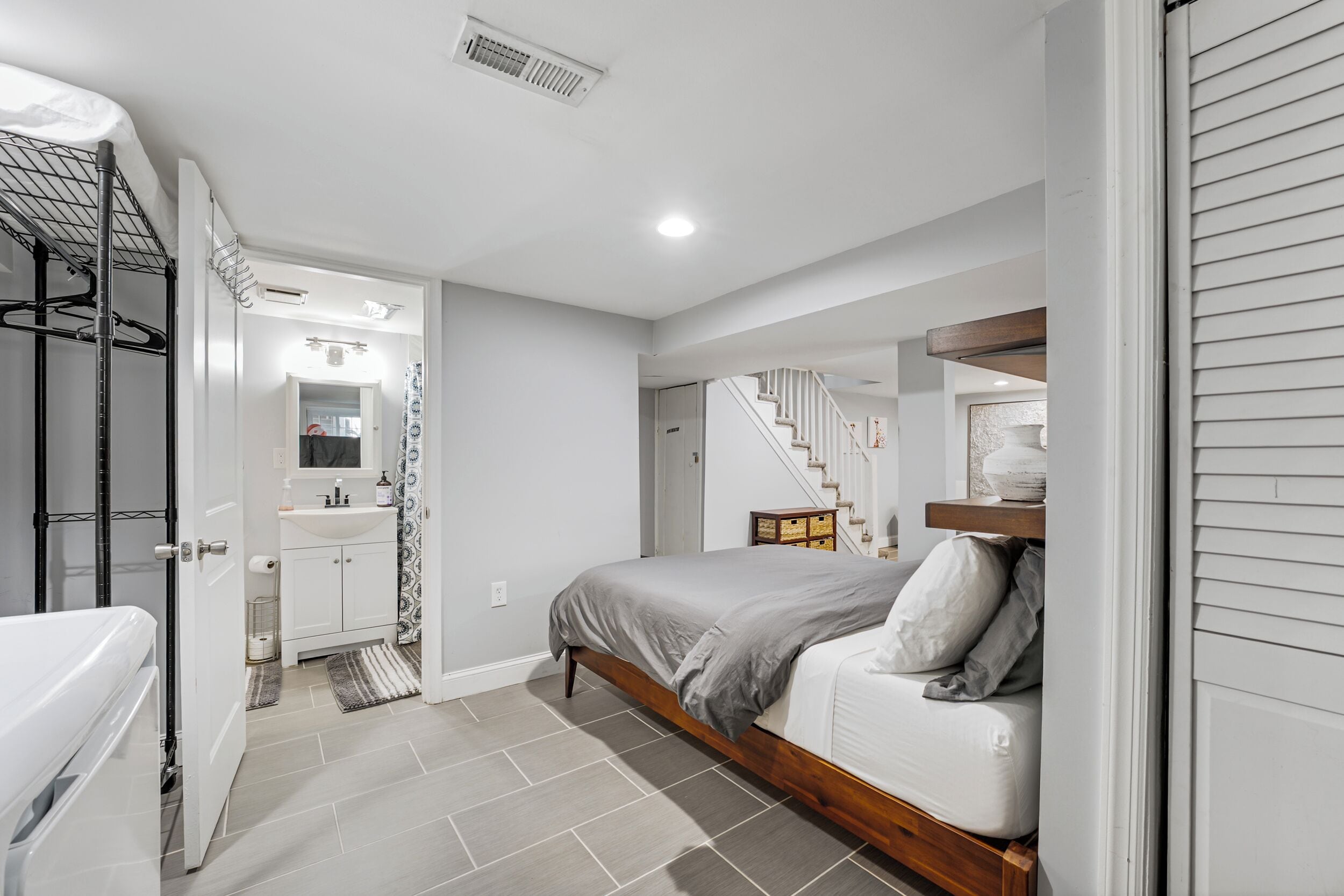 Une chambre avec un lit, une salle de bain avec un lavabo et un escalier.