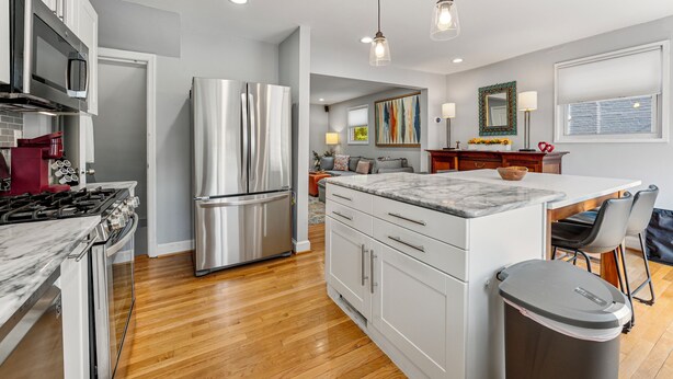A modern kitchen with stainless steel appliances, a marble countertop island, and a dining area with a sofa and chairs. - Spacious 3BR/2.5BA · Fenced Backyard Oasis · Pets OK (Washington)