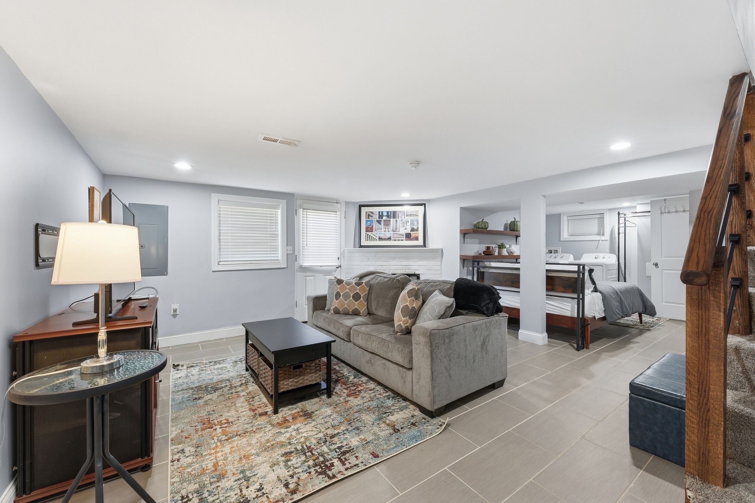A living room with a sofa, coffee table, and TV. There is a kitchen area with a dining table and chairs.