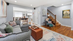 A modern living room with a grey sectional sofa, a wooden coffee table, and a staircase leading to an upper level. - Spacious 3BR/2.5BA · Fenced Backyard Oasis · Pets OK (Washington)