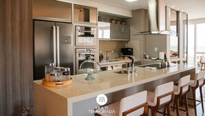 Een moderne keuken met een groot kookeiland, roestvrijstalen apparatuur en barstoelen.