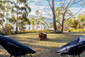 A campsite with a fire pit surrounded by trees and a view of a lake.