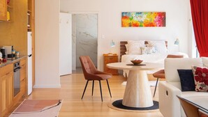 Un salon moderne avec une table basse ronde en bois, un canapé, une table à manger avec des chaises et un coin cuisine doté de meubles en bois.