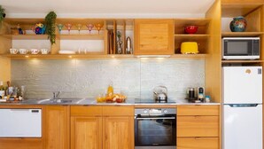 Une cuisine moderne avec des meubles en bois, un four encastré, un four à micro-ondes et un évier.