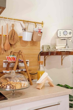 A kitchen with wooden utensils, a coffee machine, a bread display, and a hanging rack with kitchen tools. - Domus Auri Vatican Jacuzzi Boutique Stay (Roma)