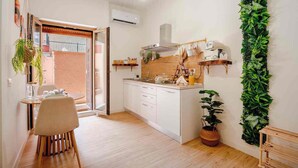 A modern kitchen with white cabinets, a wooden countertop, and a hanging plant. - Domus Auri Vatican Jacuzzi Boutique Stay (Roma)