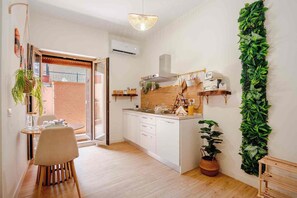 A modern kitchen with white cabinets, a wooden countertop, and a hanging plant. - Domus Auri Vatican Jacuzzi Boutique Stay (Roma)