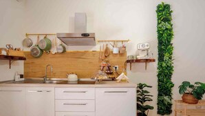 A modern kitchen with white cabinetry, a wooden backsplash, and a vertical garden. - Domus Auri Vatican Jacuzzi Boutique Stay (Roma)