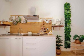 A modern kitchen with white cabinetry, a wooden backsplash, and a vertical garden. - Domus Auri Vatican Jacuzzi Boutique Stay (Roma)