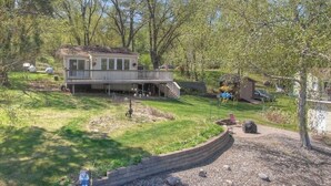 A house with a deck, surrounded by trees and a well-maintained lawn.