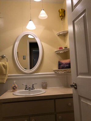 A bathroom with a round mirror, a sink, a towel rack, and a shelf with decorative items. - Pet Friendly home with hot tub and access to Taylor Park (Largo)