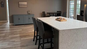 A modern kitchen with a central island, dining chairs, a ceiling fan, and a refrigerator. - Pet Friendly Pool Home close to IRB and Walsingham Park (Seminole)