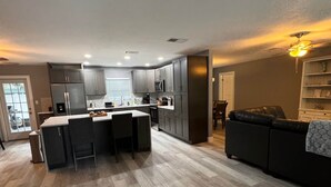 A modern kitchen with grey cabinets, a central island, and a dining area. - Pet Friendly Pool Home close to IRB and Walsingham Park (Seminole)