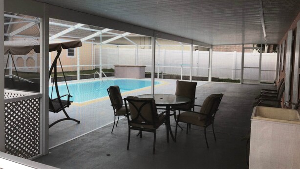 Ett takförsett utomhusområde med en pool, sittplatser och en gunga.
