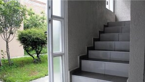 Un escalier avec une porte en verre donnant sur un espace extérieur agrémenté de verdure.