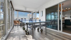 Una habitación amplia con mesa de ping pong, ventanas grandes y vistas al exterior.