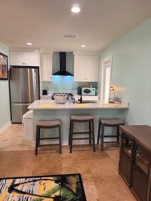 Una cocina moderna con un refrigerador de acero inoxidable, una campana extractora negra y una pared azul claro.