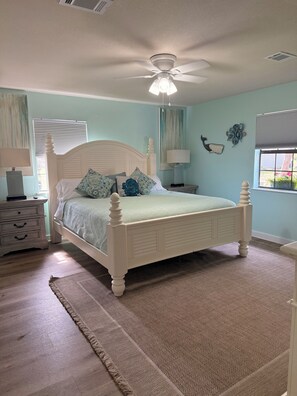 A bedroom with a bed, a nightstand, a lamp, a ceiling fan, and a window. - Peacfull 1 bedroom house with AC in charming Gulf Breeze (Gulf Breeze)
