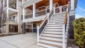 A multi-story residential building with a staircase leading to the upper floor, a covered porch, and a stone pillar. - 10th Street Beach Block Condo (Ocean City)