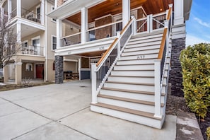 Ein mehrgeschossiges Wohngebäude mit einer Treppe zum oberen Stockwerk, einer Veranda und einer Steinsäule.