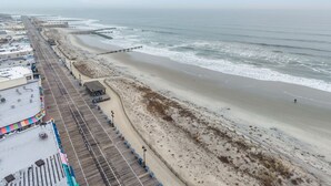 A coastal view with a beach, promenade, and buildings along the shore. - 10th Street Beach Block Condo (Ocean City)