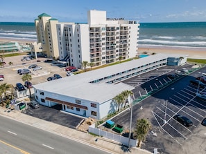 A multi-story hotel with a parking lot and a beach view. - Ocean Breeze Resort 106 (Daytona Beach Shores)