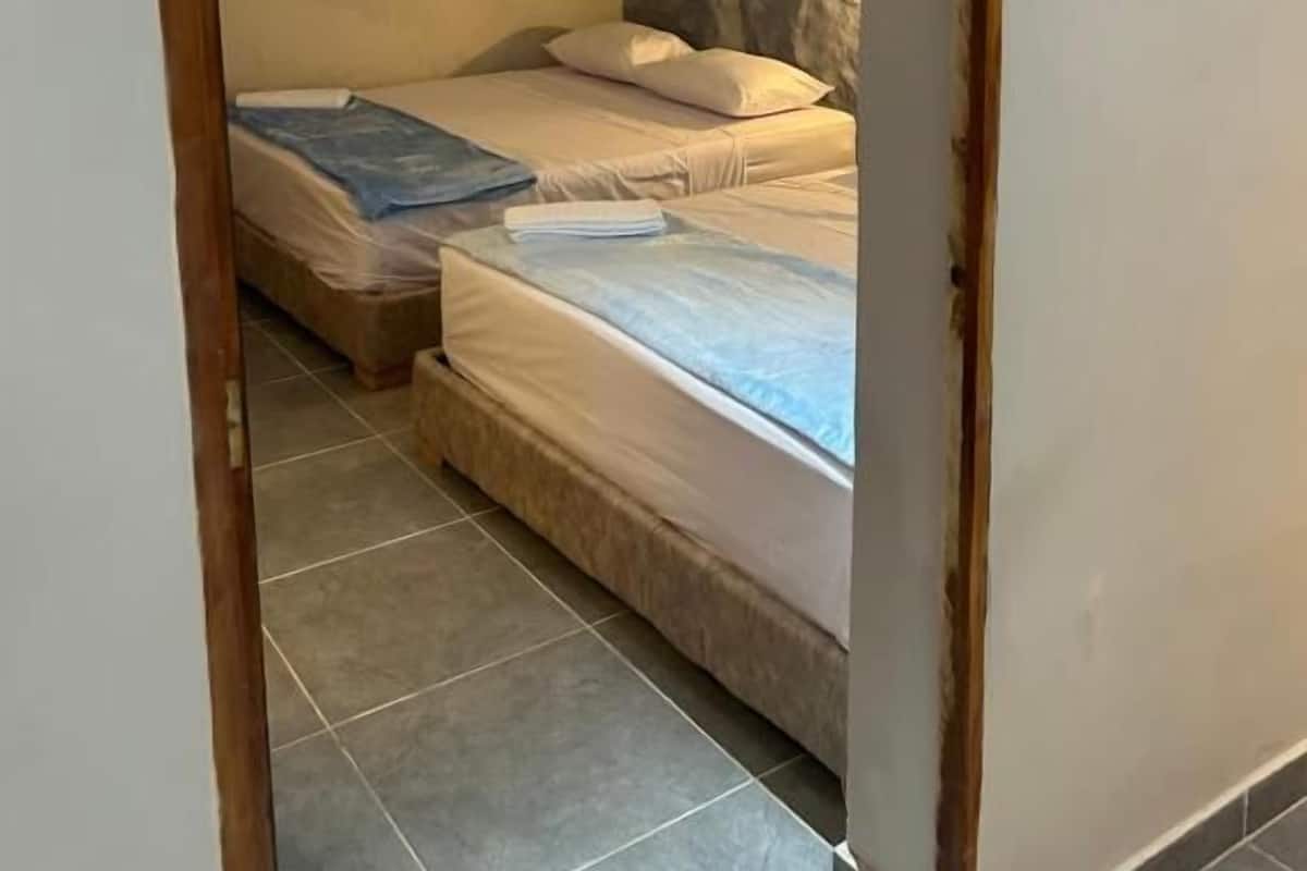 Una habitación con dos camas, aire acondicionado de pared y una lámpara.