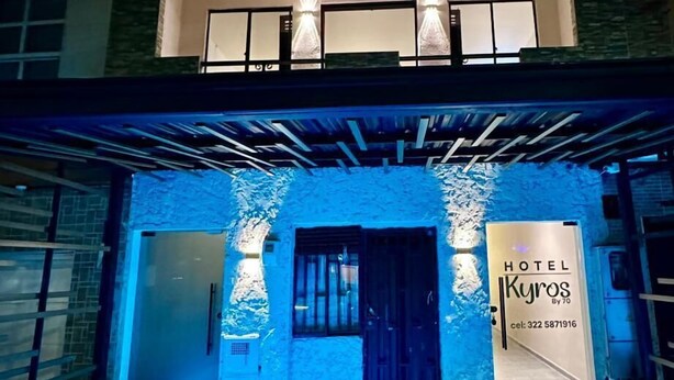 Fachada de hotel de diseño moderno, con un letrero llamativo, dos puertas y una escalera que conduce a la entrada.