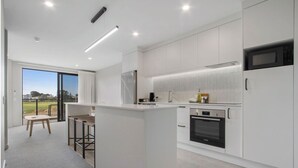 A modern kitchen with white cabinetry, a Bosch oven, and a large window offering a view of the outdoors.