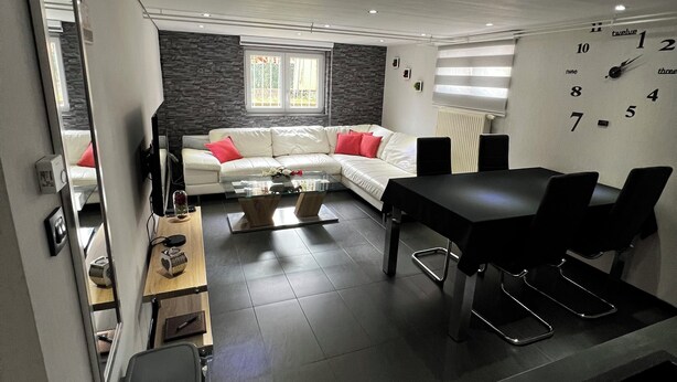 Een moderne woonkamer met een bank, een eettafel en een keukenhoek.