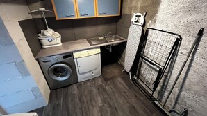 Een kleine wasruimte met een wasmachine, een droogrek en een wasbak.