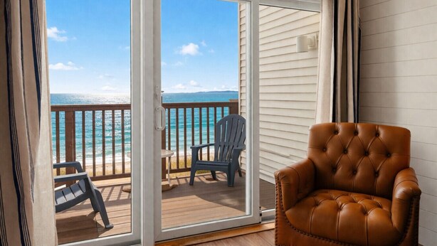 Un balcone con vista sull'oceano, una poltrona in pelle marrone e un tavolino con una sedia.