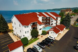 A multi-story hotel with a swimming pool, parking lot, and ocean view. - Stateroom 322|Beachfront Condo|Downtown + Tart Trail (Traverse City)