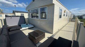 Une maison mobile dotée d’un patio comprenant un jacuzzi, des sièges d’extérieur et une petite table.