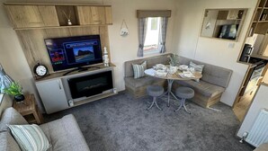 Un espace de vie compact comprenant un canapé, une petite table, un téléviseur et une kitchenette.