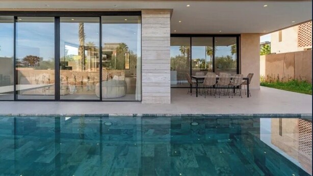 A modern house with a swimming pool, large glass windows, and a patio with outdoor furniture. - Sumptuous Villa with swimming pool in the secure estate of MYSK Route d'amizmiz (Marrakech)