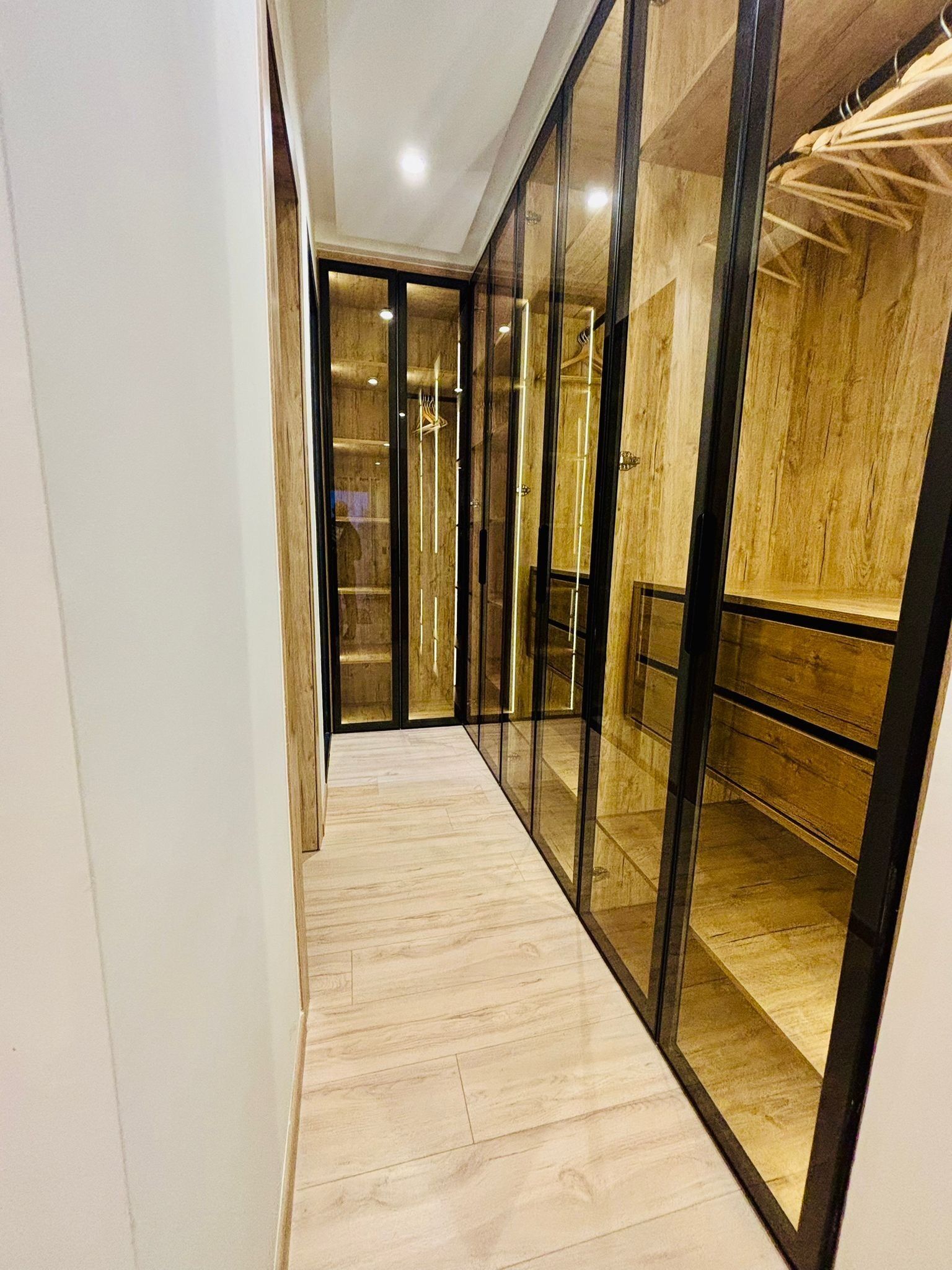 Un couloir doté d’un plancher en bois, de portes en verre et d’un mur en bois.
