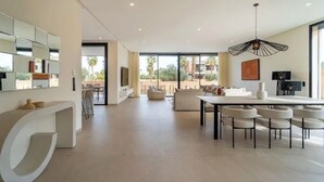 A modern interior with a dining area, a large white console, and a view to the outside. - Sumptuous Villa with swimming pool in the secure estate of MYSK Route d'amizmiz (Marrakech)