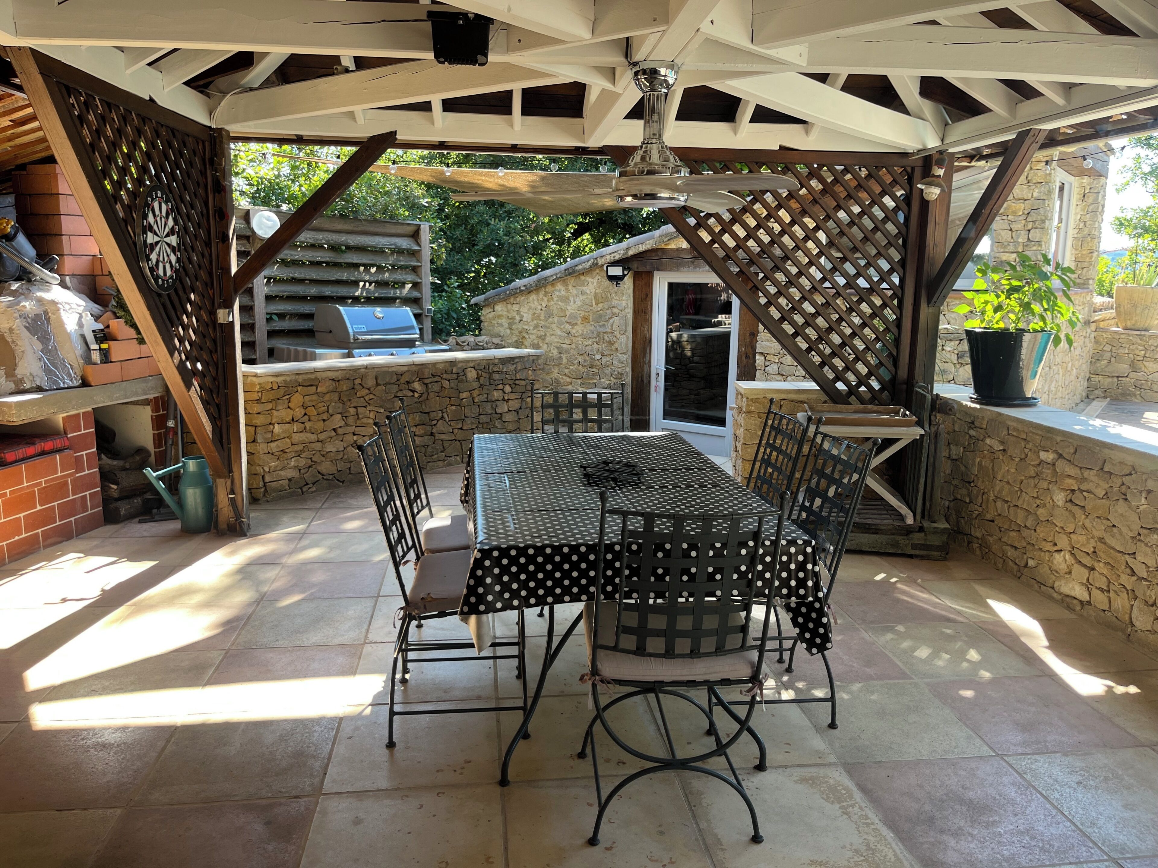 Un patio exterior con mesa y sillas, una parrilla y un muro de piedra.