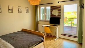 Ett sovrum med en säng, ett skrivbord, en stol, en tv och ett fönster med utsikt.