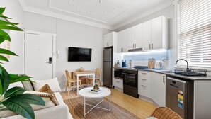 A modern kitchen with white cabinets, a built-in oven, and a dishwasher. - Bondi Salt Soul - A Sepal Stay (Sydney)