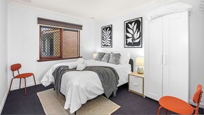 Ein Schlafzimmer mit einem Bett, zwei Stühlen, einem Nachttisch, einem Kleiderschrank und Bildern an der Wand.