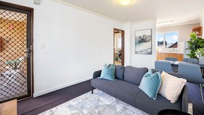 Ein Wohnzimmer mit grauem Sofa, einem Couchtisch und einem Essbereich mit Stühlen und Tisch.