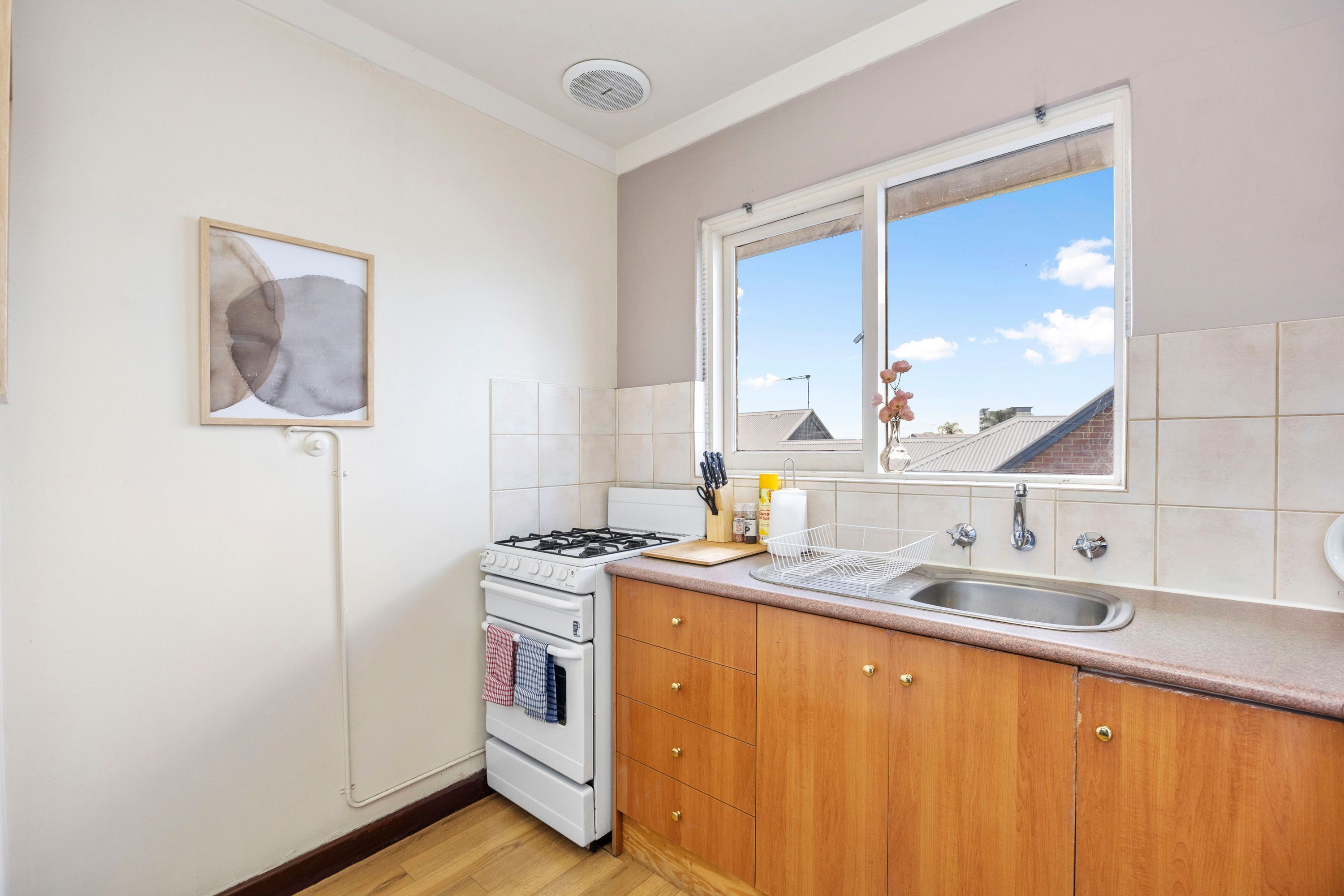 A kitchen with a stove, oven, sink, and window with a view of buildings.