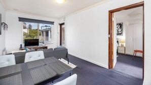 Ein modernes Wohnzimmer mit Essbereich, Fernseher und Blick ins Freie.