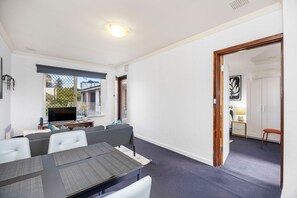 A modern living room with a dining area, a TV, and a view of the outside. - Skynest Rivervale - Sepal Stay (Perth)