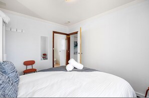 A hotel room with a large bed, a red chair, a wooden door, and a mirror on the wall. - Skynest Rivervale - Sepal Stay (Perth)