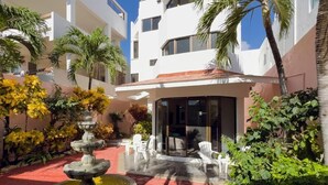 A courtyard with a fountain, outdoor seating, and a building with a modern design. - Casa 4 Estaciones (Puerto Morelos)